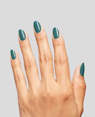 Hand with medium skin tone displaying neatly manicured nails painted in Baby Tee-l, a rich teal OPI nail polish nail lacquer shade, against a light gray background to showcase the glossy color and smooth coverage.