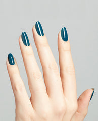 Hand with long oval nails painted in Drama at La Scala, a glossy deep teal OPI nail polish, shown against a clean light gray background to highlight the rich color and smooth nail lacquer finish.