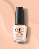OPI Suzi Take a Vow nail lacquer bottle in a soft peachy nude shade stands upright with a black cap on a matching peach background, a subtle choice for fall nail colors.