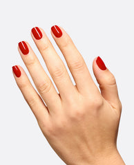 Hand displays glossy deep red OPI Vodka & Caviar nail lacquer on rounded nails, a classic shade for fall nail colors against a clean light gray background.