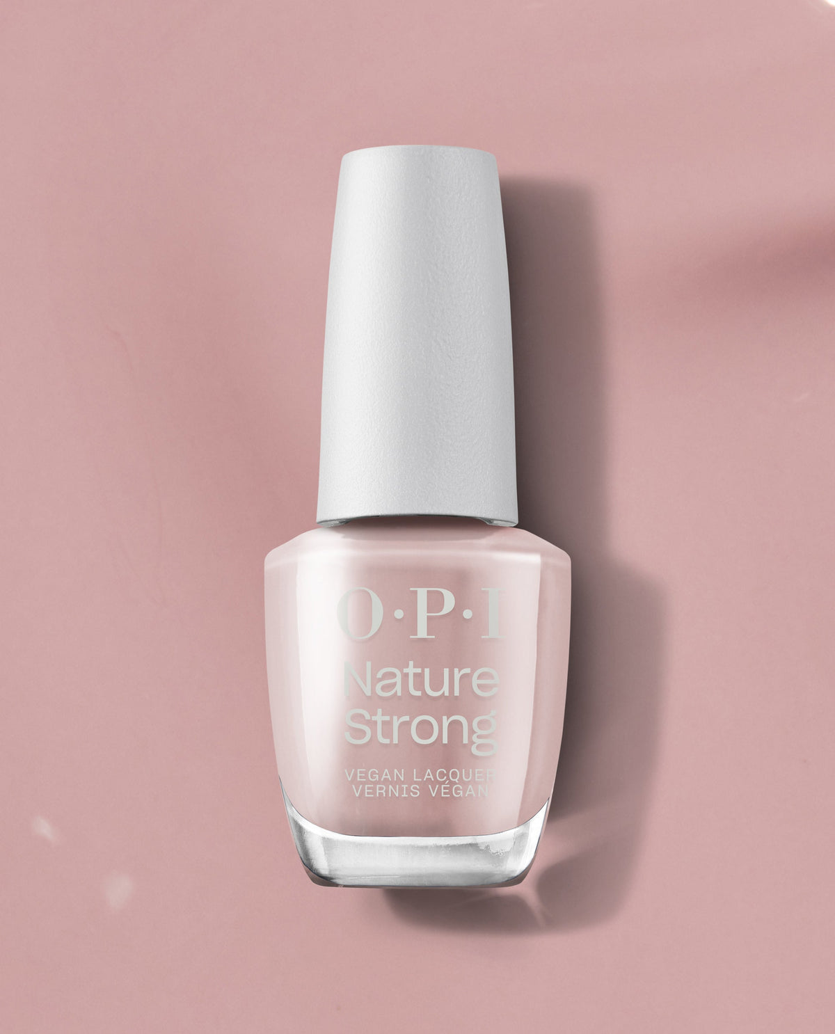 OPI Nature Strong Vegan Nail Lacquer in Kind of a Twig Deal stands upright, showing a soft pale pink shade with a white cap on a dusty pink background, ideal for subtle fall nail colors.