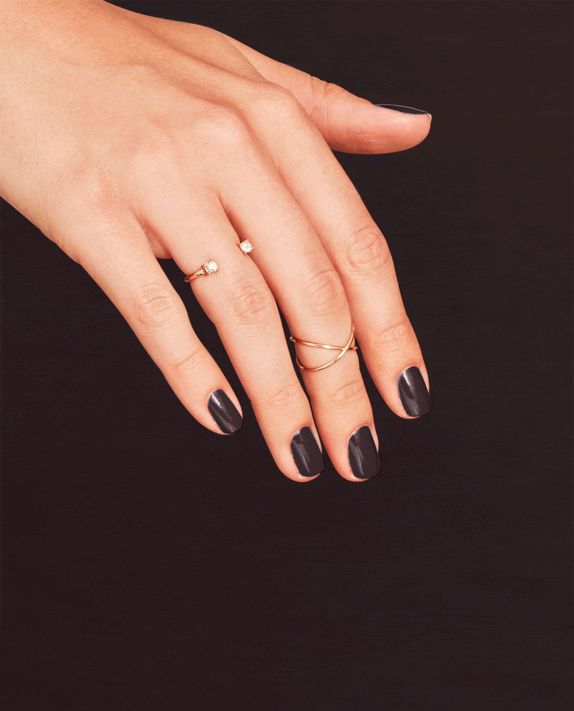 Hand modeling OPI Brown to Earth nail lacquer, a glossy deep brown shade for fall nail colors, with gold rings against a dark background.