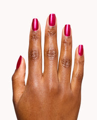 Hand modeling OPI It’s All Greek to Me gel nail polish, a glossy metallic berry-magenta shade on short rounded nails against a white background, ideal for bold fall nail colors.