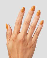 Hand with neatly manicured nails painted in Penny Loafer Lane, a warm caramel orange OPI nail polish shade, shown against a light gray background to highlight the glossy nail lacquer color and smooth finish.