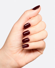 Hand modeling glossy deep burgundy OPI Vampire State Building nail lacquer on short rounded nails, showcasing rich fall nail colors against a clean white background.